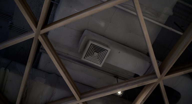 Technicien installant une VMC avec gaines de ventilation dans une cave.