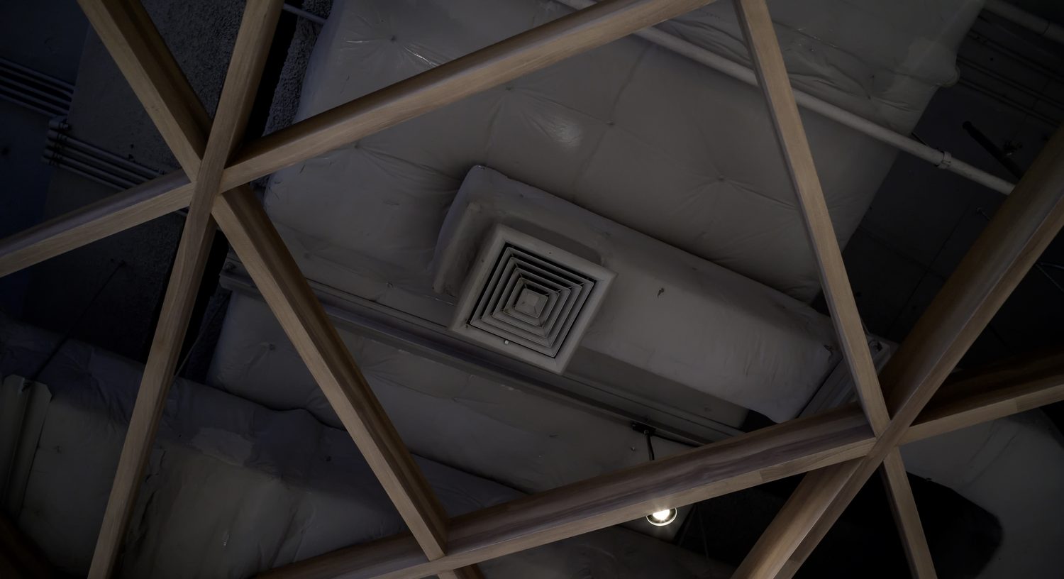 Technicien installant une VMC avec gaines de ventilation dans une cave.